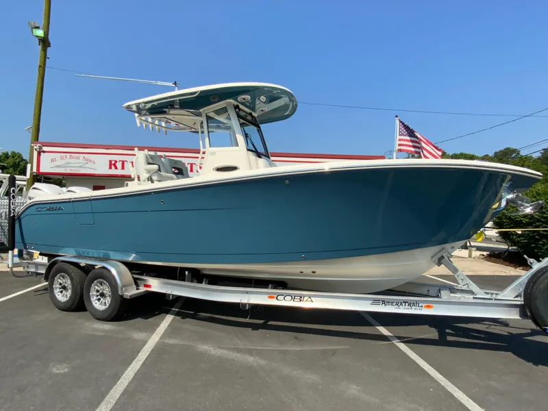 Slide: The Image of 2025 Cobia 265 CC center console boat on a trailer in a parking lot. - 1
