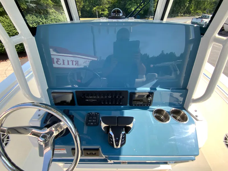 Slide: The Image of Cobia 265 CC 2025 boat dashboard with steering wheel, controls, and cup holders. - 27