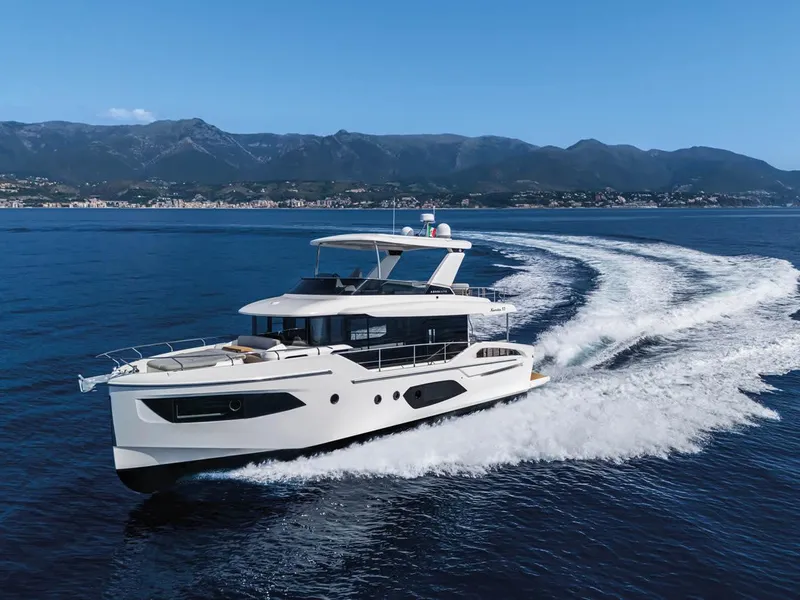 Slide: The Image of 2025 Absolute 53 Navetta yacht cruising on open water with scenic mountain backdrop. - 2