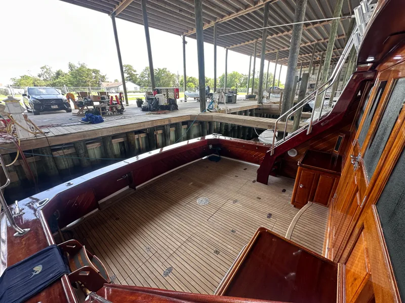 Slide: The Image of 1980 Bertram 58 Convertible Custom yacht interior with wooden deck and dock view. - 12