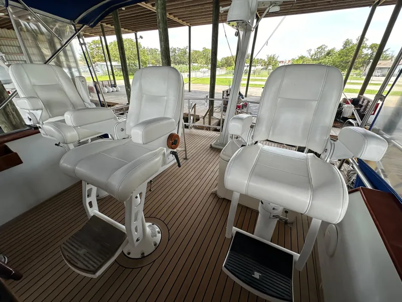 Slide: The Image of 1980 Bertram 58 Convertible Custom yacht with white captain chairs on teak deck. - 19