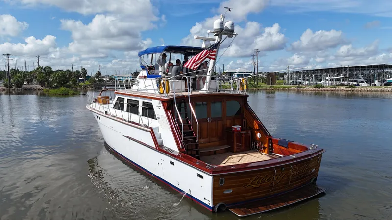 Slide: The Image of 1980 Bertram 58 Convertible Custom yacht on calm water, featuring classic design and American flag. - 5