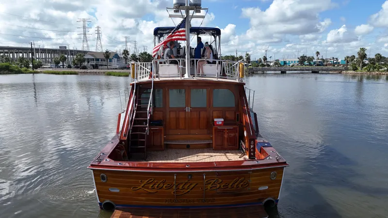 Slide: The Image of 1980 Bertram 58 Convertible Custom yacht on calm water, rear view with American flag. - 6