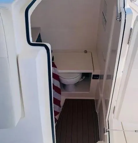 Slide: The Image of 2021 Cobia 330 Dual Console boat interior with toilet and storage area. - 26