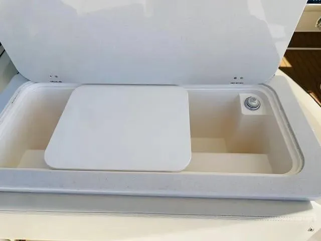 Slide: The Image of 2021 Cobia 330 Dual Console storage compartment with lid open. - 32