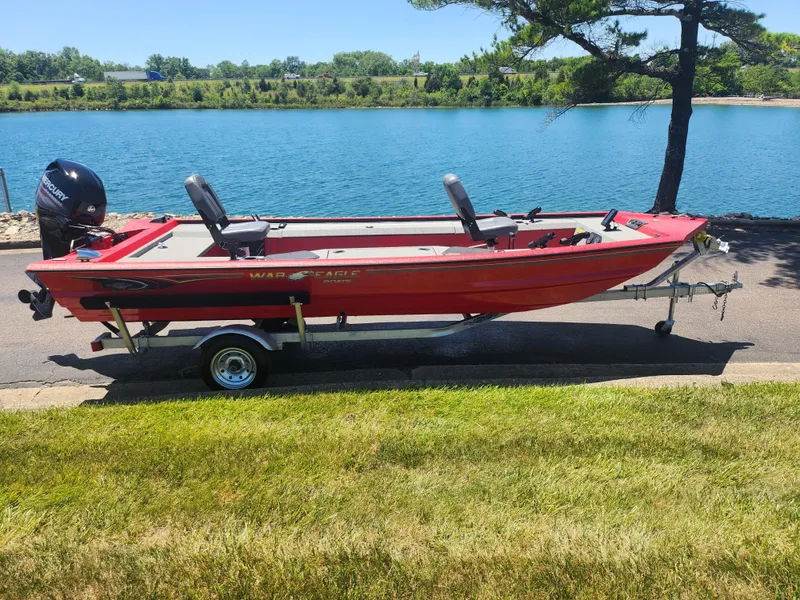 Slide: The Image of 2018 War Eagle 754VS Stick Steer boat on trailer by a lake. - 9