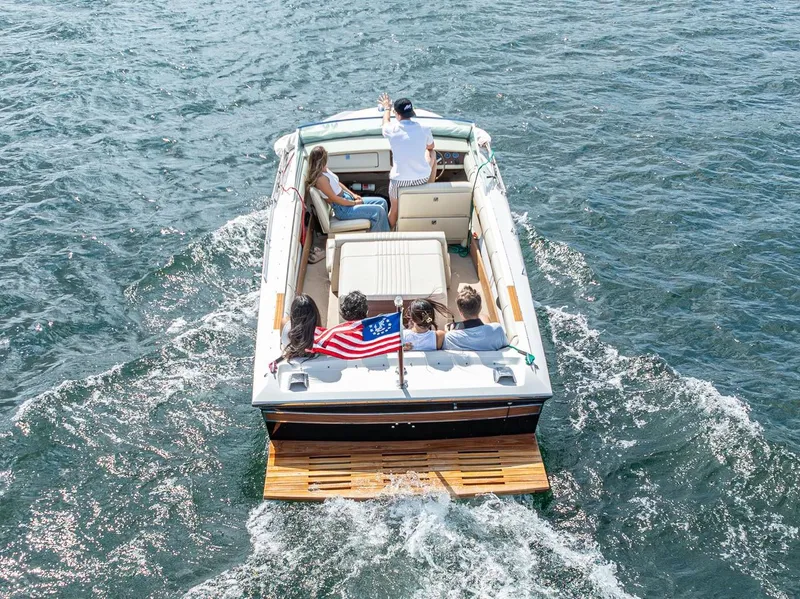 Slide: The Image of 1973 Century Coronado boat with passengers cruising on a lake, American flag displayed. - 12