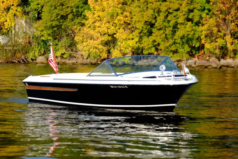 Slide: The Image of 1973 Century Coronado boat on a calm lake with autumn foliage in the background. - 8