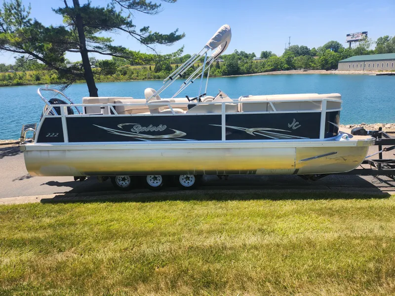 Slide: The Image of 2019 JC 222 Spirit pontoon boat on a trailer by a lake. - 8