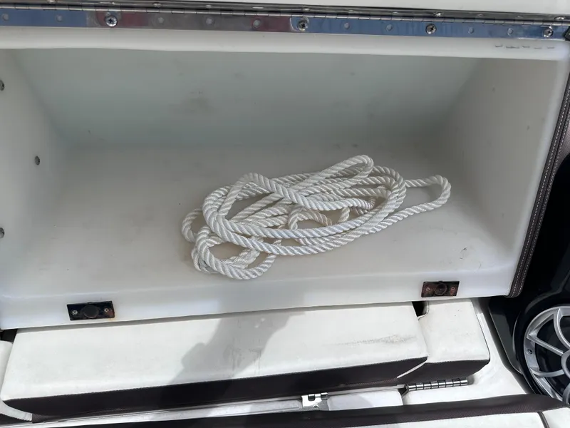 Slide: The Image of Storage compartment with white rope on a 2021 Yamaha Boats 252 SD. - 10