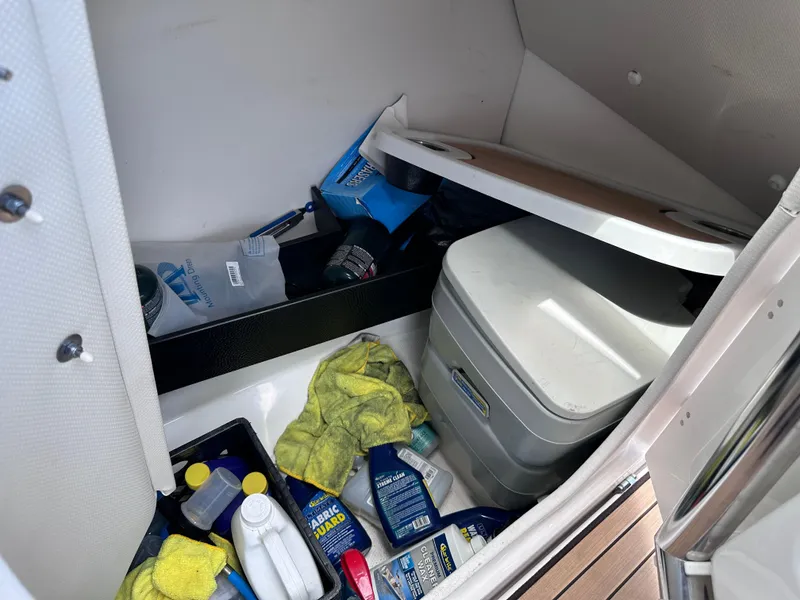 Slide: The Image of Storage compartment of 2021 Yamaha Boats 252 SD with cleaning supplies and portable toilet. - 19