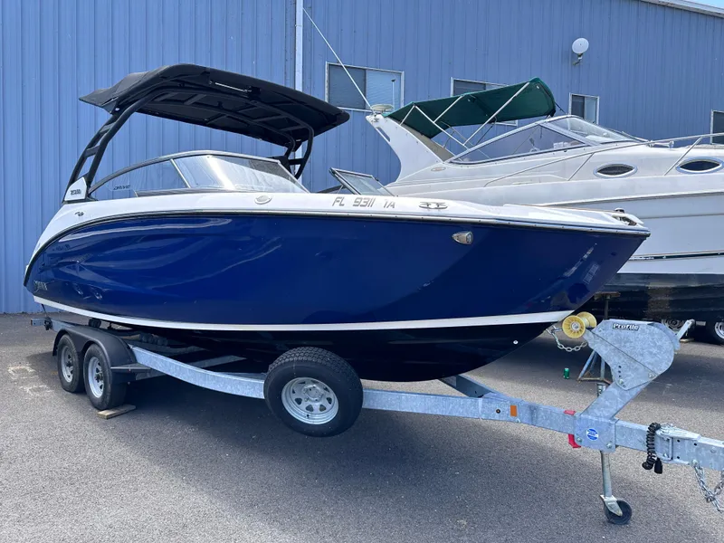 Slide: The Image of 2021 Yamaha Boats 252 SD on trailer, blue hull, parked near blue building. - 2