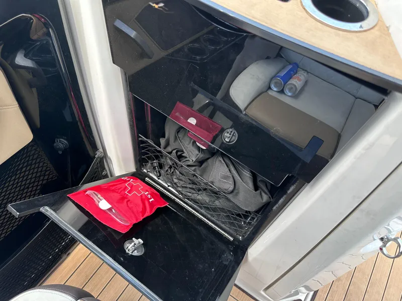 Slide: The Image of Storage compartment in a 2021 Yamaha Boats 252 SD, with first aid kit and drinks. - 20