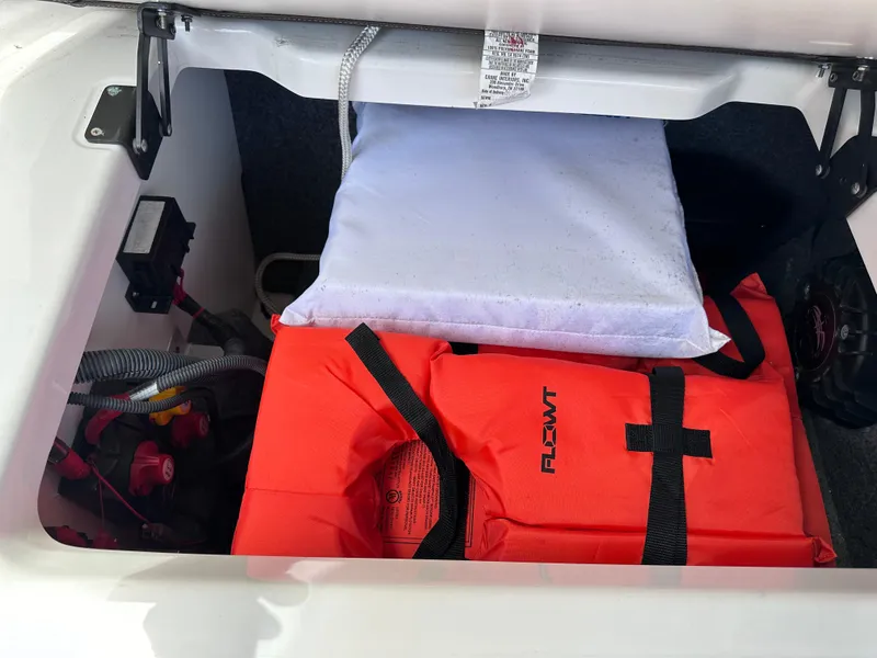 Slide: The Image of Storage compartment of a 2021 Yamaha Boats 252 SD with life jackets and equipment. - 26