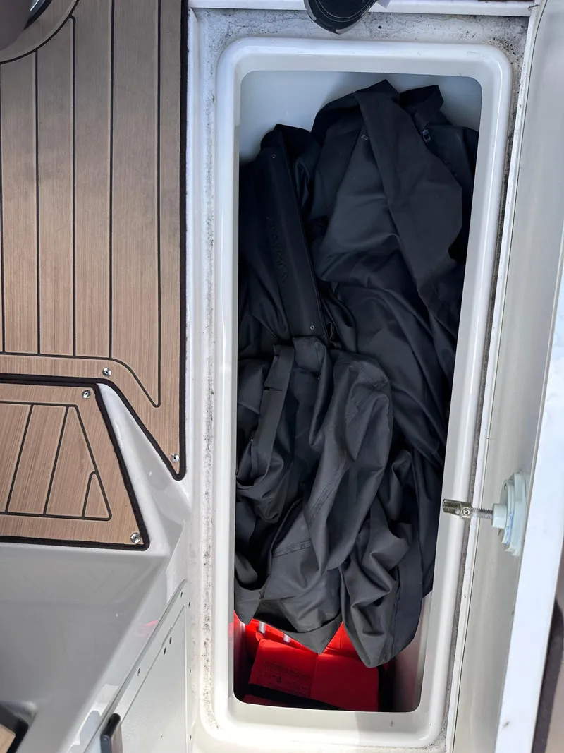 Slide: The Image of Storage compartment on a 2021 Yamaha Boats 252 SD, containing black fabric and a red item. - 34