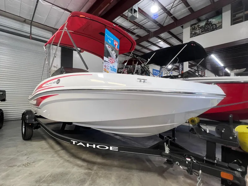 Slide: The Image of 2024 Tahoe T16 boat with red canopy on display in showroom. - 2
