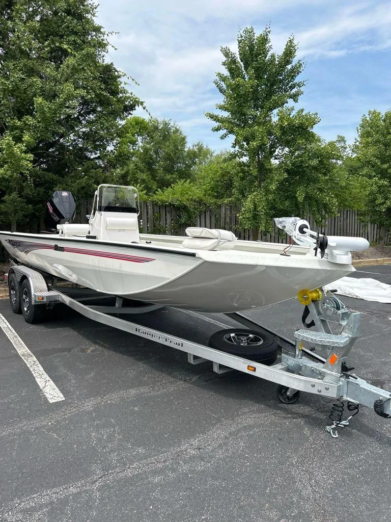 Slide: The Image of 2024 Ranger RB210 boat on trailer in parking lot, surrounded by trees. - 1