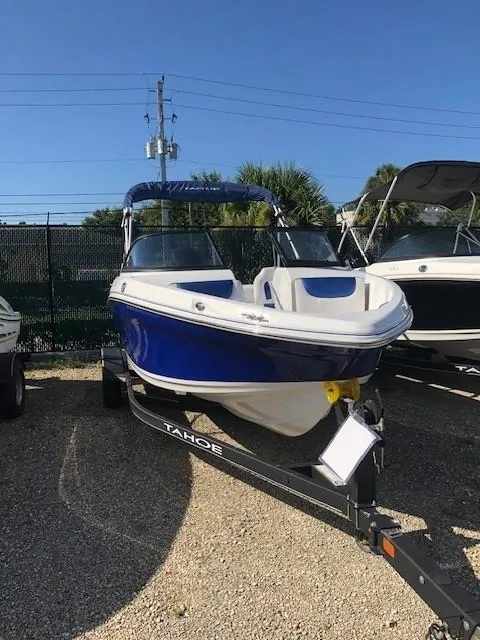 Slide: The Image of 2024 Tahoe 200 S boat on trailer, blue and white design, parked outdoors. - 1