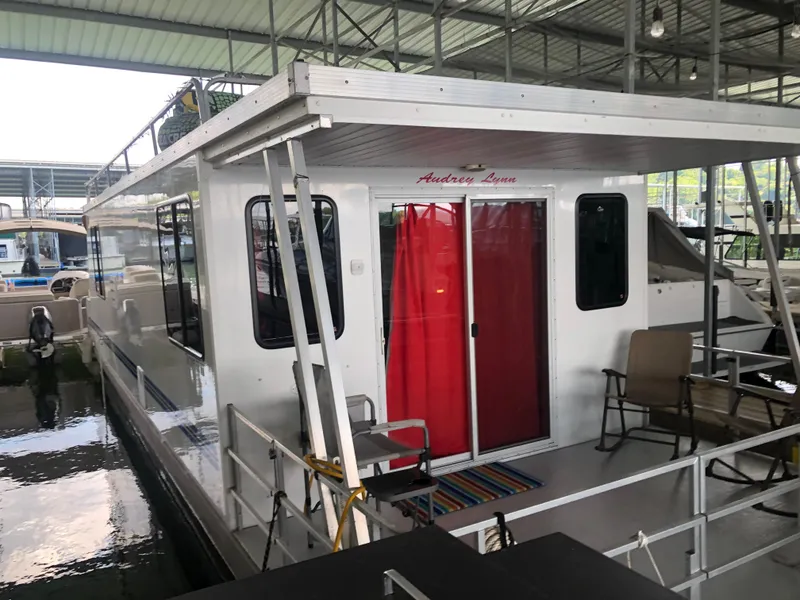 Slide: The Image of 2013 Catamaran Cruisers 39 houseboat docked with red curtains and outdoor seating. - 32