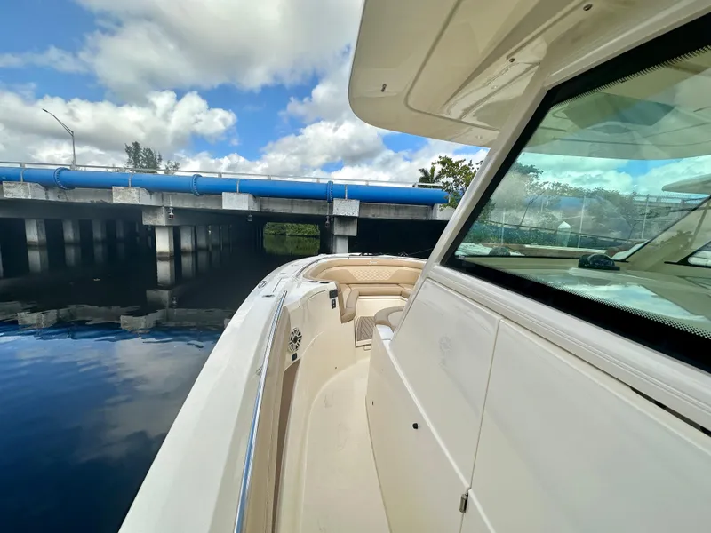 Slide: The Image of 2025 Scout 330 LXF boat cruising near a bridge on a sunny day. - 9