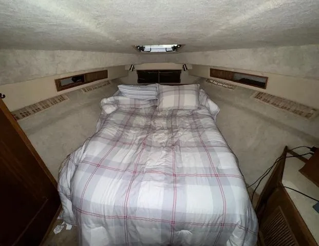 Slide: The Image of 1986 Sea Ray 340 Express Cruiser cabin with cozy bed and plaid bedding. - 6