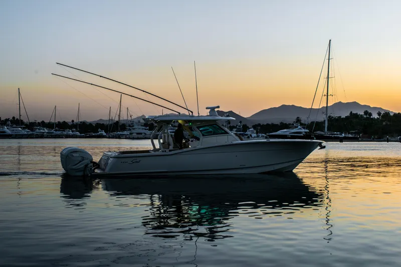 Slide: The Image of 2020 Scout 380 LXF boat cruising at sunset in a marina. - 2