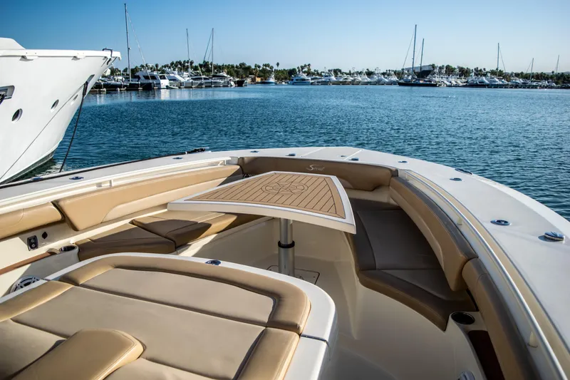 Slide: The Image of 2020 Scout 380 LXF boat interior with tan seating and table, docked in a marina. - 34