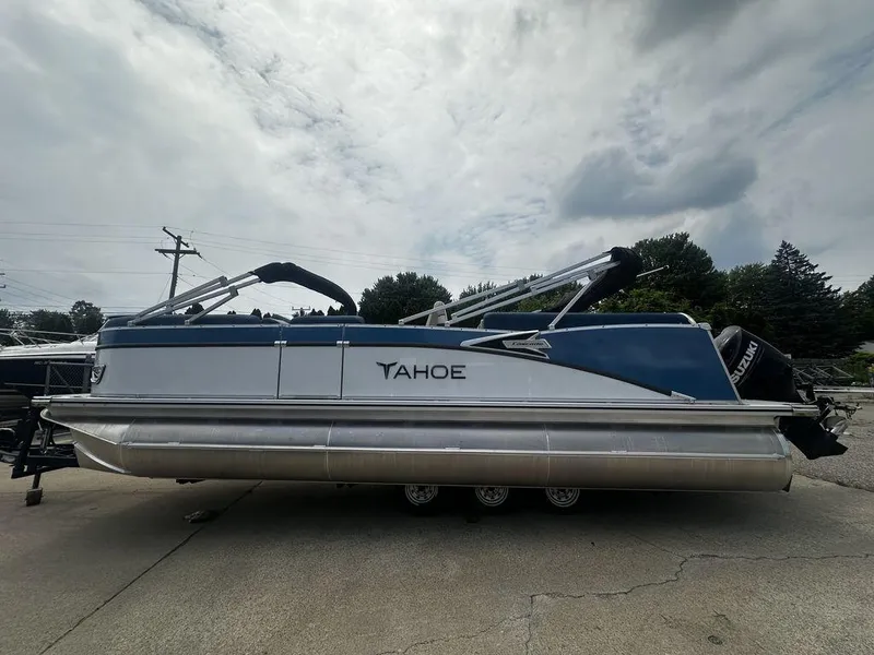 Slide: The Image of 2024 Tahoe CASCADE 2385 QL pontoon boat with Suzuki engine, parked outdoors. - 0