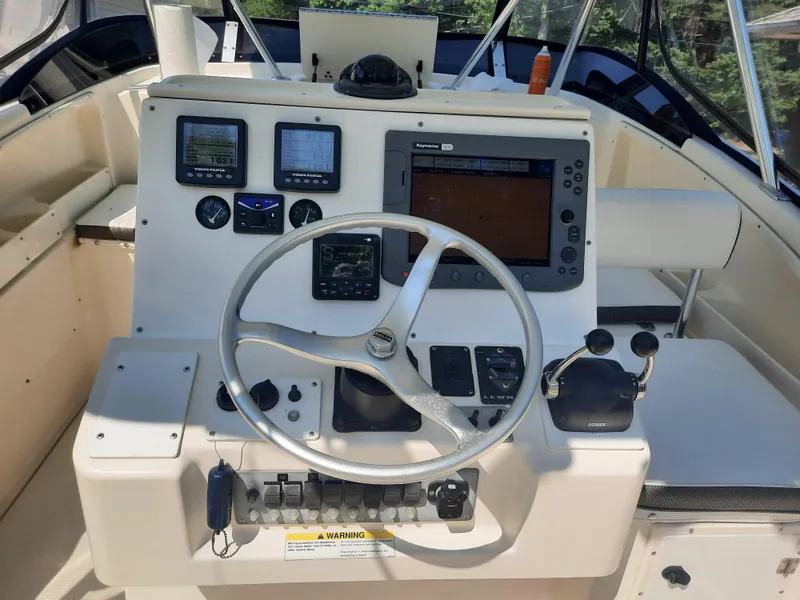 Slide: The Image of 1998 Pursuit 2800 Offshore boat helm with navigation instruments and steering wheel. - 10