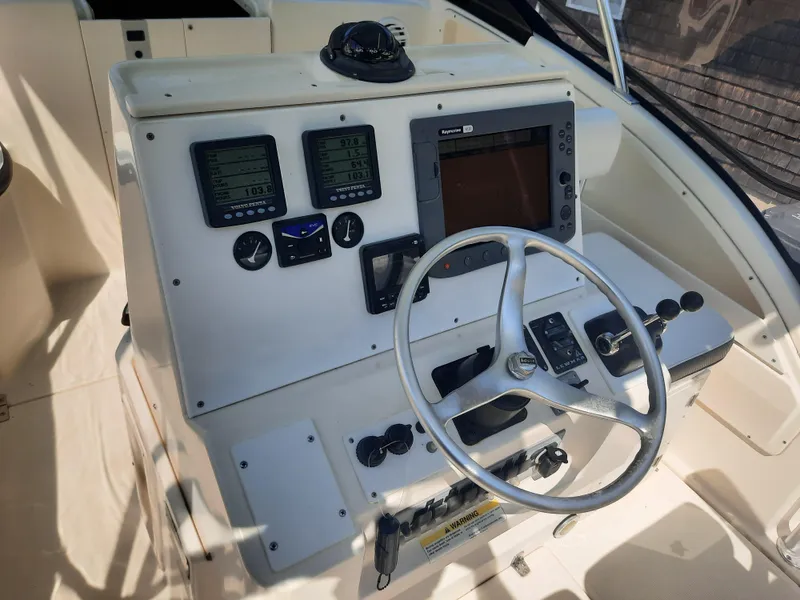 Slide: The Image of 1998 Pursuit 2800 Offshore boat helm with navigation instruments and steering wheel. - 11