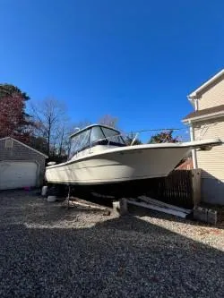 Slide: The Image of 1998 Pursuit 2800 Offshore boat on gravel driveway near house. - 3