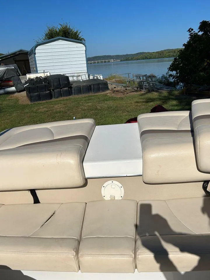 Slide: The Image of 2006 Chaparral 210 SSi boat with beige seating, near a lake and storage shed. - 11
