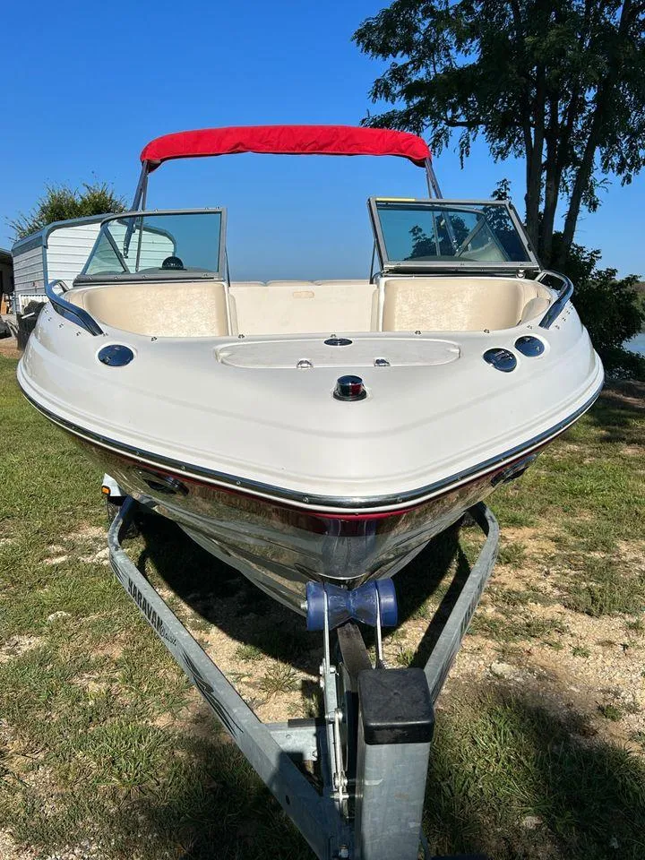 Slide: The Image of 2006 Chaparral 210 SSi boat with red canopy on trailer, parked on grass. - 18