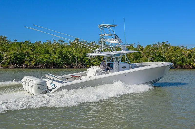 Slide: The Image of 2019 Bahama 41 boat cruising on a sunny day, surrounded by lush greenery. - 14