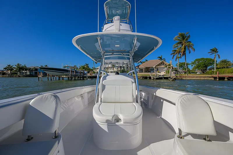 Slide: The Image of 2019 Bahama 41 boat with sleek white seating, docked near palm trees and waterfront homes. - 25
