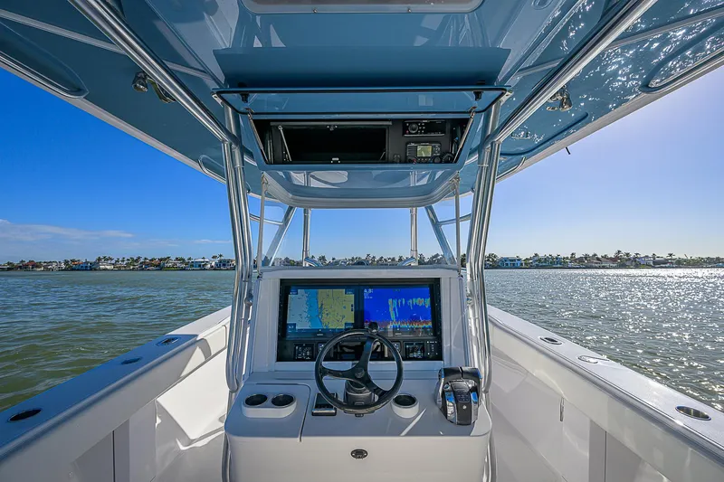 Slide: The Image of 2019 Bahama 41 boat cockpit with navigation system, steering wheel, and ocean view. - 29
