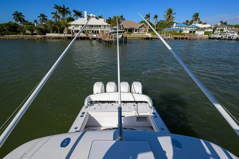 Slide: The Image of 2019 Bahama 41 boat with multiple engines, docked near waterfront homes and palm trees. - 49