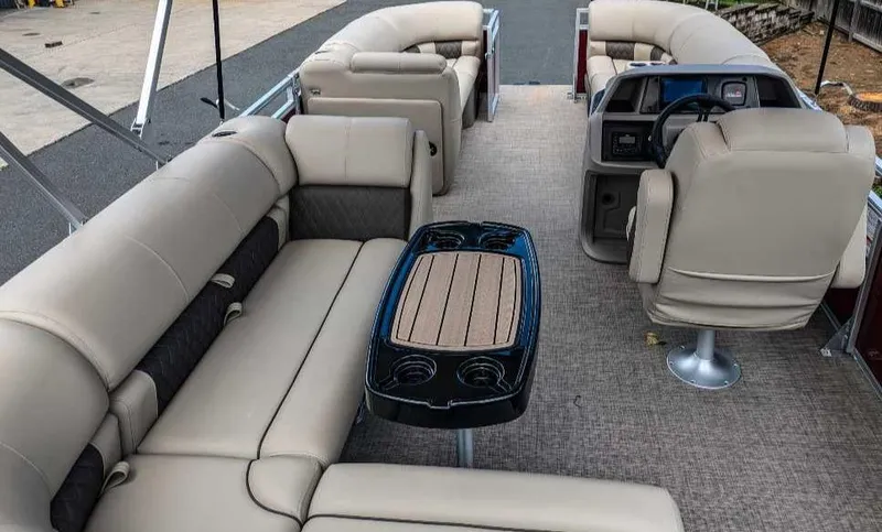 Slide: The Image of 2024 Sun Tracker Party Barge 20 DLX interior with beige seating and central table. - 16