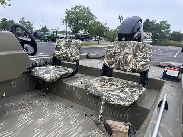 Slide: The Image of 2024 Tracker Grizzly 1754 SC boat with camo seats and steering wheel. - 2