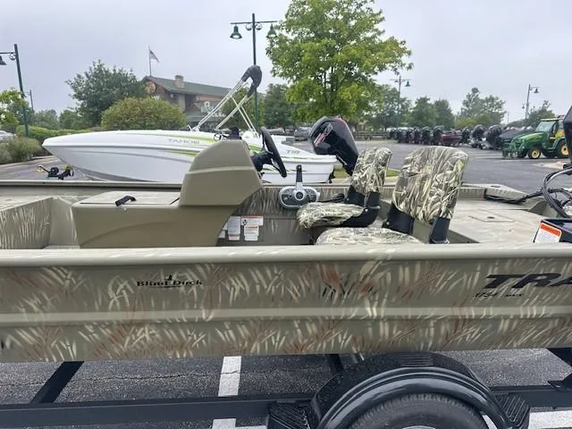 Slide: The Image of 2024 Tracker Grizzly 1754 SC boat with camouflage seats in a parking lot. - 3