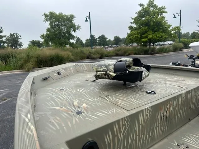 Slide: The Image of 2024 Tracker Grizzly 1754 SC boat with camouflage design in a parking lot. - 4