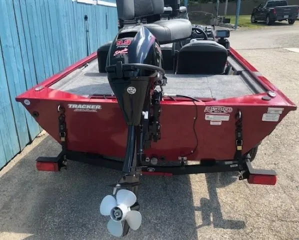 Slide: The Image of 2024 Tracker Pro 170 boat, rear view with motor, red color, parked near blue fence. - 5