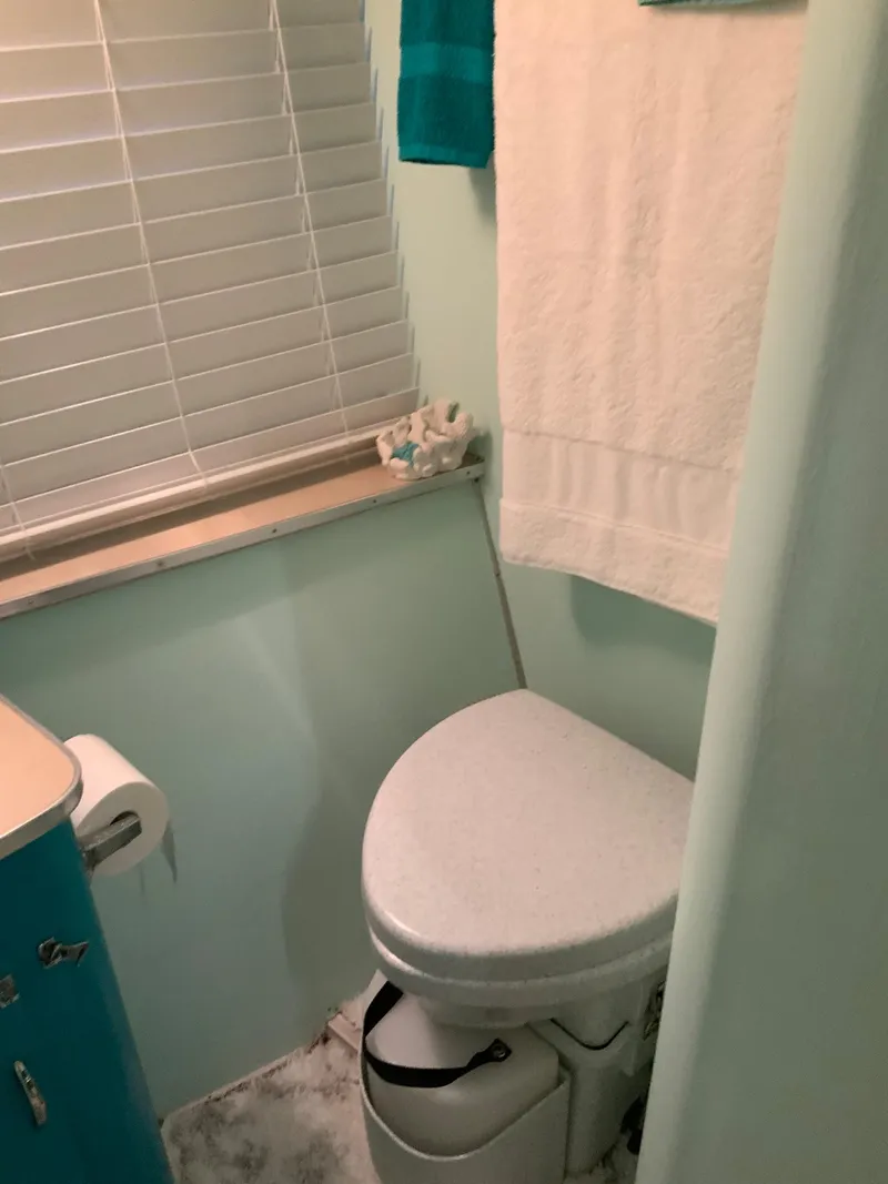 Slide: The Image of 1969 Hatteras 41 Double Cabin bathroom with toilet, towel, and window blinds. - 43