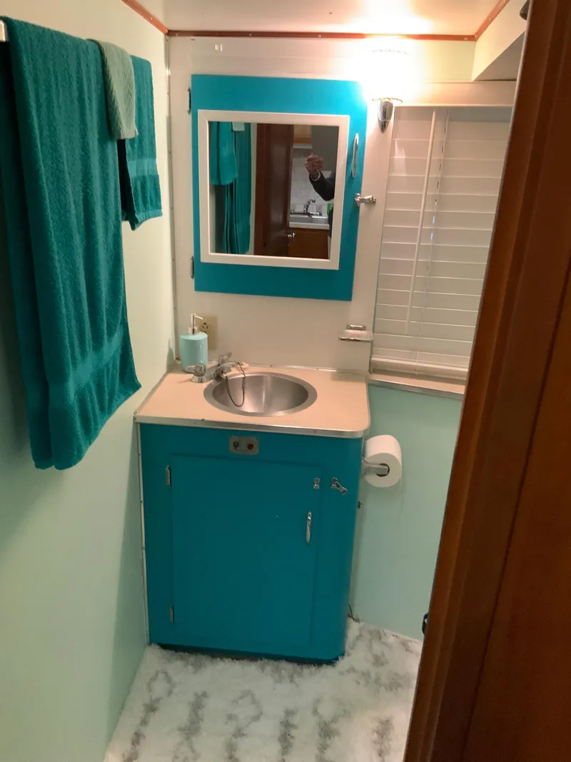 Slide: The Image of 1969 Hatteras 41 Double Cabin bathroom with teal vanity and towels. - 44