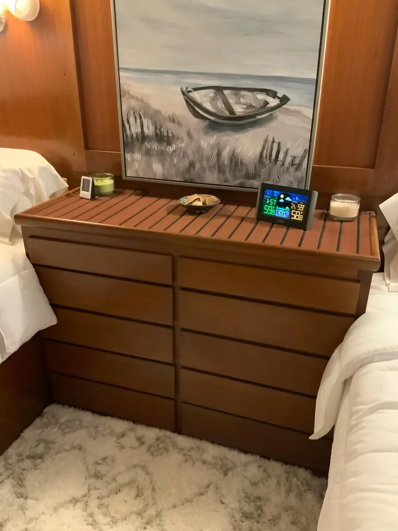 Slide: The Image of Wooden dresser in a 1969 Hatteras 41 Double Cabin with beach-themed decor. - 49