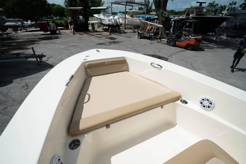 Slide: The Image of 2025 Scout 195 Sportfish boat with beige cushioned seating at a marina. - 2