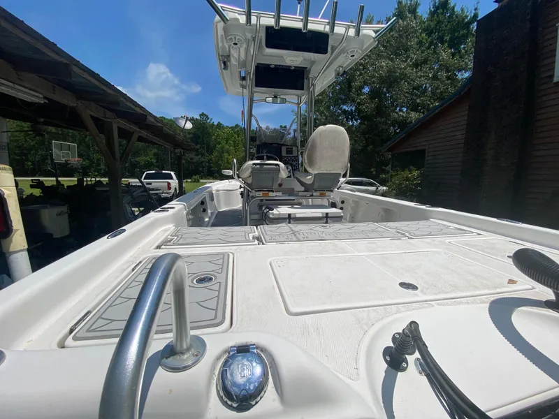 Slide: The Image of 2019 Blue Wave 2400 PureBay boat, spacious deck, center console, and T-top, parked outdoors. - 25