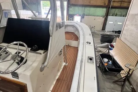 Slide: The Image of 1976 SeaCraft 23 Classic boat interior with wooden deck, steering wheel, and dockside view. - 6