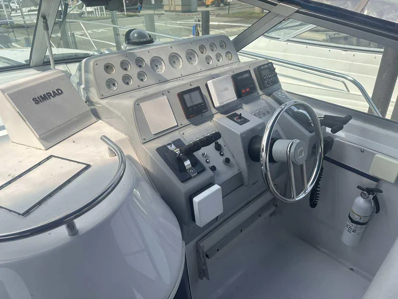 Slide: The Image of Control panel of a 1992 Four Winns 365 Express boat with steering wheel and navigation instruments. - 12