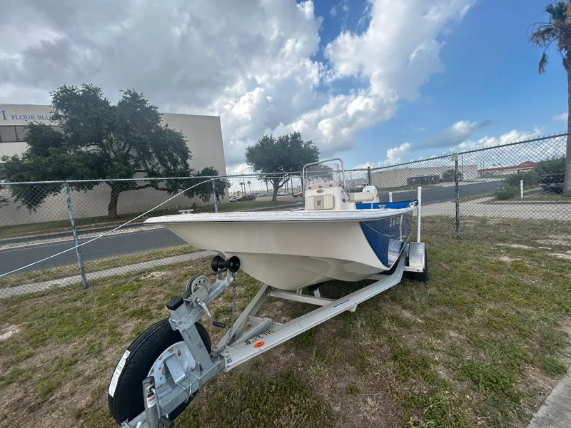 Slide: The Image of 2019 Carolina Skiff 198 DLV boat on a trailer, parked outdoors under a cloudy sky. - 2